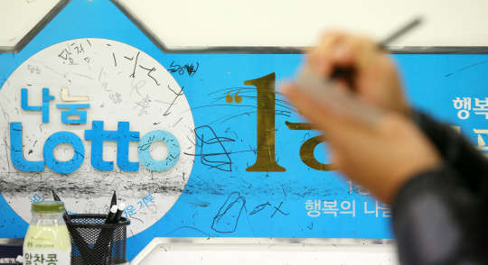 미국에서 복권 광풍을 일으킨 파워볼 복권의 영향으로 국내에서도 복권에 대한 관심이 높아지고 있다. 15일 오후 서울 노원구의 한 로또 판매점에서 한 시민이 신중하게 번호를 표시하고 있다.